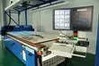 Industrial cutting machine with digital control monitors in a production facility, used for precision manufacturing of sealing and technical component materials.