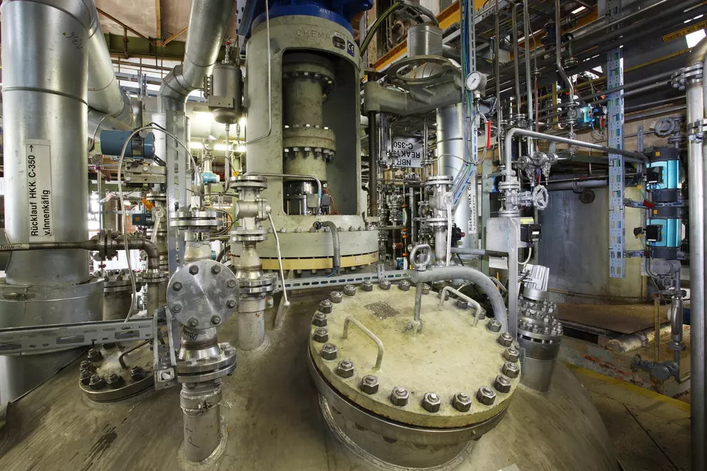 Industrial processing vessel with piping and sealed access cover in a production plant.