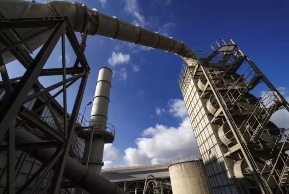 Industrial processing facility with large pipes and towers under a clear sky.