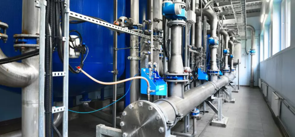Moderne industrielle Wasseraufbereitungsanlage mit Edelstahlrohrleitungen, Pumpen und automatisierten Steuerungssystemen.